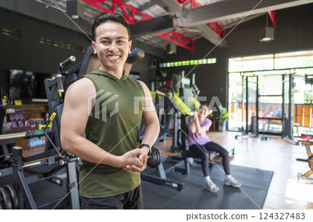 Indonesian southeast asian man showing his arm muscles after training in the gym. Fitness exercise and healthy lifestyle concept 124327483