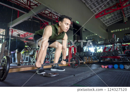 Indonesian southeast asian man working out while lifting a barbell at the gym. Fitness exercise and healthy lifestyle concept 124327520