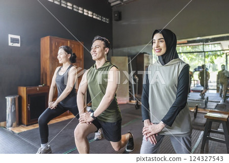 Chinese east asian and arab middle eastern muslim women with indonesian southeast asian men working out and stretching in a yoga class at the gym. Fitness exercise and healthy lifestyle concept 124327543