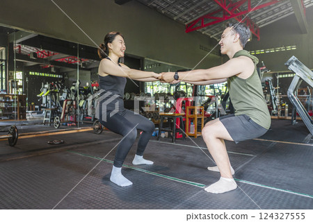 Chinese east asian woman and indonesian southeast asian man working out and stretching in a yoga class at the gym. Fitness exercise and healthy lifestyle concept Chinese east asian woman and indonesian southeast asian man working out and stretching in a yoga class at the gym. Fitness exercise and healthy lifestyle concept 124327555