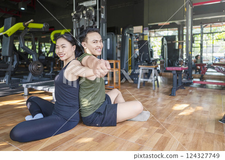Chinese east asian woman and indonesian southeast asian man working out and stretching in a yoga class at the gym. Fitness exercise and healthy lifestyle concept 124327749