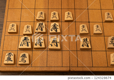Shogi pieces are lined up on a shogi board. They are fighting in a turret enclosure. 124328674