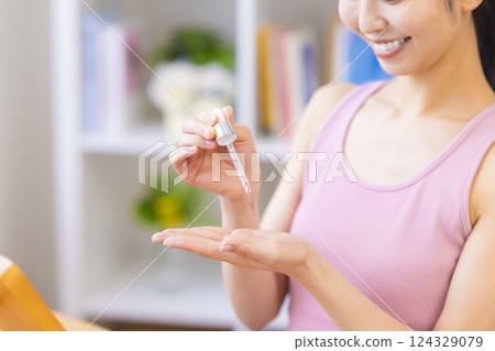 美容圖片：一位女士將美容精華液滴在手上 124329079