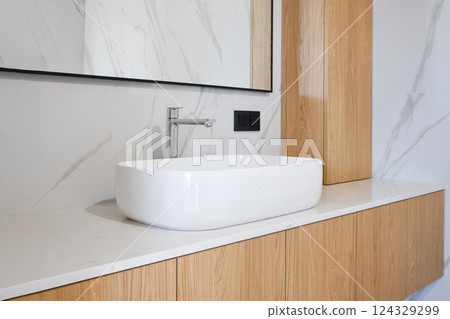 Modern bathroom design with sleek sink and wooden cabinetry in contemporary setting Modern bathroom design with sleek sink and wooden cabinetry in contemporary setting 124329299