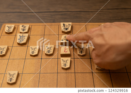 Shogi board and shogi pieces in the hands of a person who is checking the opponent Shogi board and shogi pieces in the hands of a person who is checking the opponent 124329916