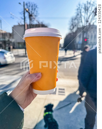 Hand Holding Takeaway Coffee Cup on City Street, Sunny Day, Urban Lifestyle, Beverage, Outdoor Scene. High quality photo Hand Holding Takeaway Coffee Cup on City Street, Sunny Day, Urban Lifestyle, Beverage, Outdoor Scene. High quality photo 124330428