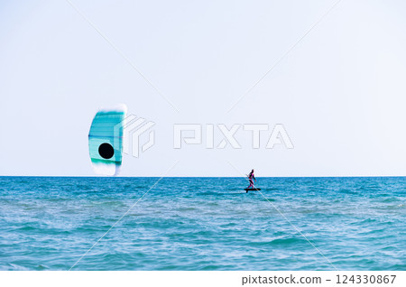 woman at sea rides a hydrofoil surfboard using a kite wing. Extreme sport, fast travel across the sea on a board woman at sea rides a hydrofoil surfboard using a kite wing. Extreme sport, fast travel across the sea on a board 124330867