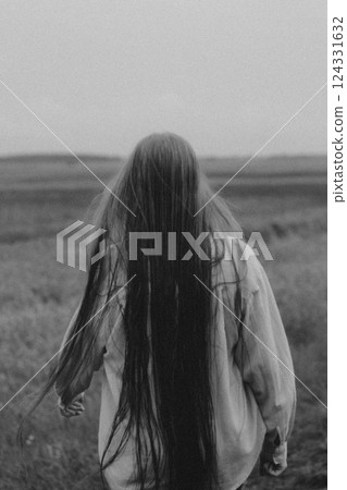 Pretty girl with a hat in her hand walks in a field with field flowers and smiles sincerely. Pretty girl with a hat in her hand walks in a field with field flowers and smiles sincerely. 124331632
