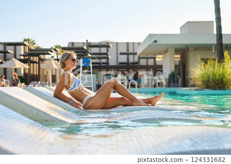 A girl sits near the pool after spa treatments. Turkey, hotel, vacation, travel, girl in a swimsuit 124331682