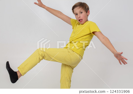 A boy in a yellow shirt and yellow pants takes a step. He is wearing black socks. Concept of playfulness and fun A boy in a yellow shirt and yellow pants takes a step. He is wearing black socks. Concept of playfulness and fun 124331906
