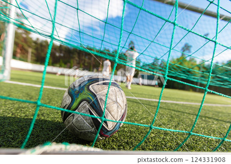 A soccer ball lies in a net on a field. Football is a sport. The concept of scoring a goal. A soccer ball lies in a net on a field. Football is a sport. The concept of scoring a goal. 124331908