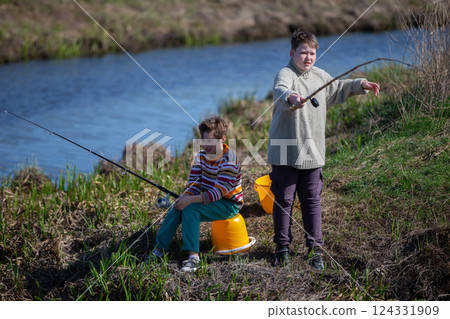 Two teenage boys fishing in a small river. 124331909