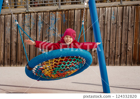 Caucasian smiling child of 8 9 years swinging on round seesaw looking at camera 124332820