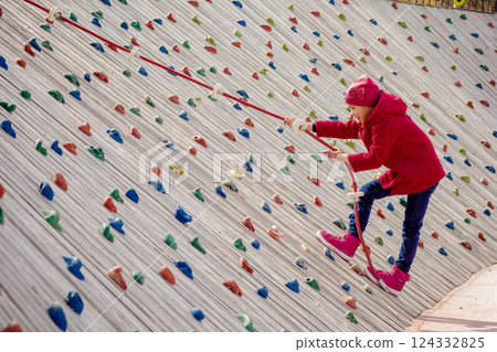 Happy child climbing on artificial rock wall on playground Happy child climbing on artificial rock wall on playground 124332825