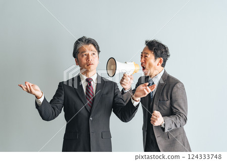 A middle-aged male business person calling out to middle-aged and elderly men through a loudspeaker 124333748