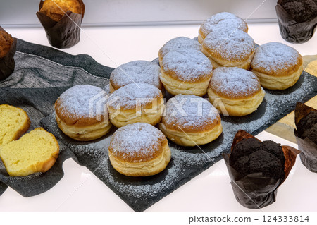 Fresh baked berliner donuts and muffins on table in cafe, top view. Fresh various pastries in bakery showcase. 124333814