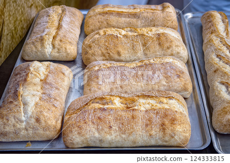 Fresh crispy ciabattas on metal tray on table in bakery, top view. Sale of baked goods in the store. 124333815
