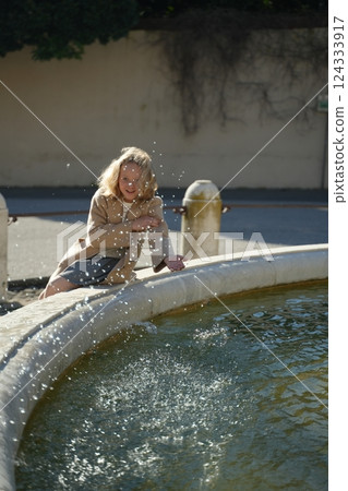Teen Girl Enjoys Water Fountain on a Sunny Day 124333917