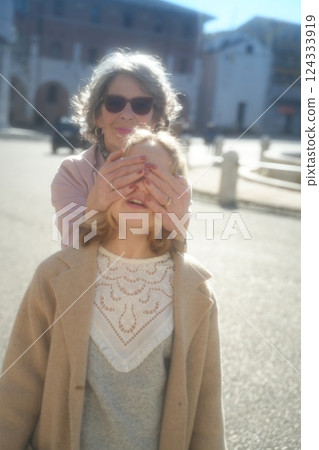 Grandmother and Granddaughter Playing Peekaboo Outdoors Grandmother and Granddaughter Playing Peekaboo Outdoors 124333919