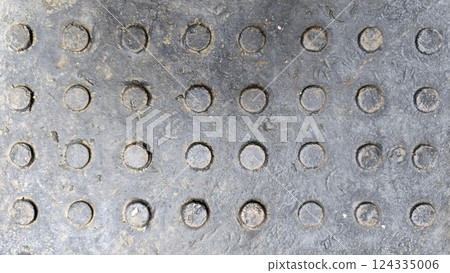 Close-up of steel metal cover texture, rough and rustic finish, low relief dot, grey color tone for background design. Close-up of steel metal cover texture, rough and rustic finish, low relief dot, grey color tone for background design. 124335006