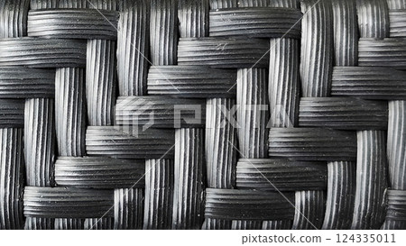 Close-up of plastic rattan furniture surface texture, black color tone for background design. 124335011