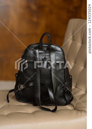 Black leather backpack on a chair Black leather backpack on a chair 124335024