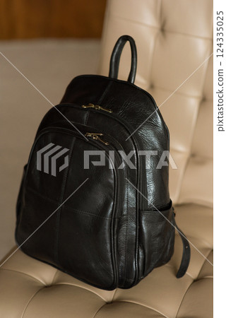 Black leather backpack on a chair Black leather backpack on a chair 124335025