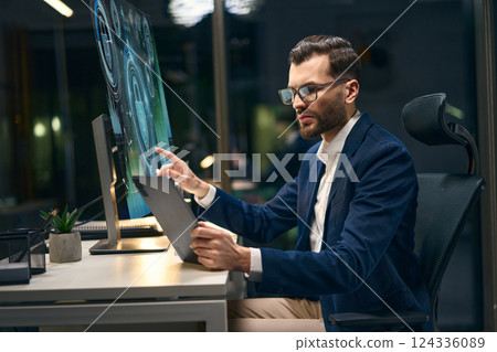 Professional Worker Using Digital Devices in Modern Office During Evening Hours 124336089