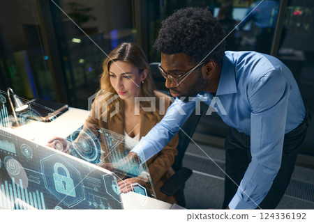 Team Collaborating on Cybersecurity Solutions Using Innovative Technology Displays in Modern Workspace 124336192