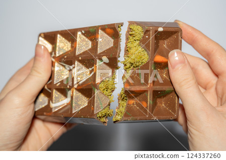 Close up of famous Dubai chocolate with pistachio, tahini and kadaif broken in woman's hands. Confectionery handmade sweets, chocolatier 124337260