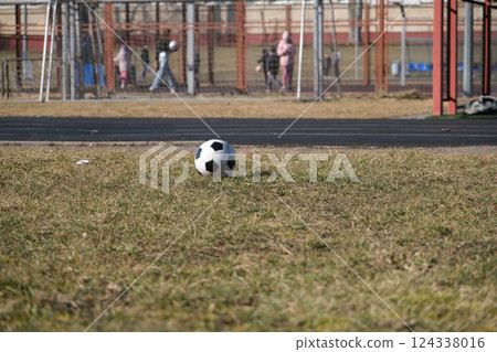 Soccer ball on children's stadium with children playing in the background Soccer ball on children's stadium with children playing in the background 124338016