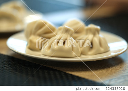 Fresh prepared Georgian dumplings of Khinkali are shown on a plate, close -up Fresh prepared Georgian dumplings of Khinkali are shown on a plate, close -up 124338028