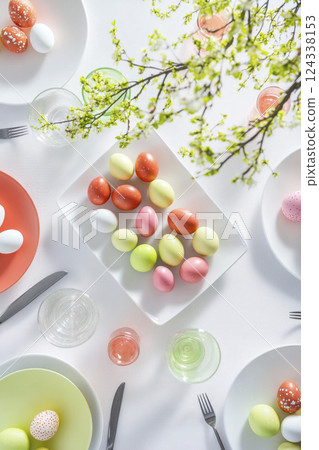 Easter light table setting Color pastel Easter eggs on plates on white Top view. Soft light, shadows Easter light table setting Color pastel Easter eggs on plates on white Top view. Soft light, shadows 124338153