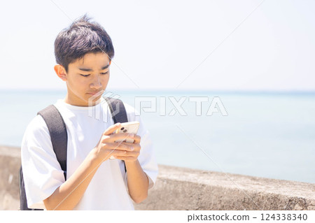 一個男孩一邊看著智慧型手機一邊搜尋地點 124338340