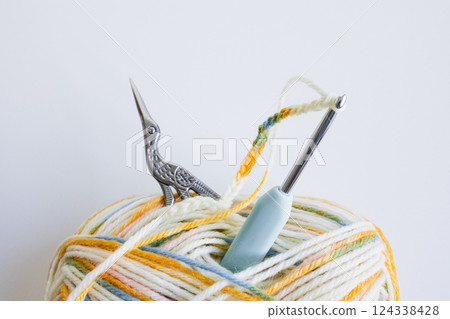 Colorful yarn ball with crochet hook and ornate scissors on white background Colorful yarn ball with crochet hook and ornate scissors on white background 124338428