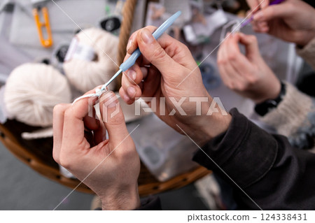 Close up of adults crocheting with yarn and hooks 124338431