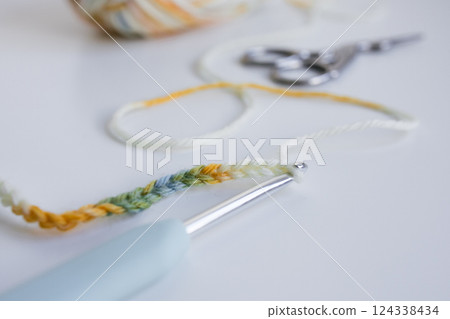 Colorful crocheting yarn with hook and scissors on white surface 124338434