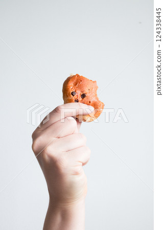 Hand holding partially eaten cookie against white background Hand holding partially eaten cookie against white background 124338445
