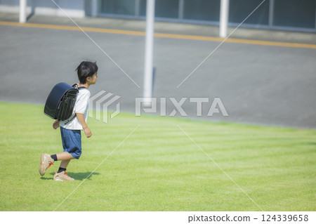 Elementary school student carrying a backpack walking outdoors Elementary school student carrying a backpack walking outdoors 124339658