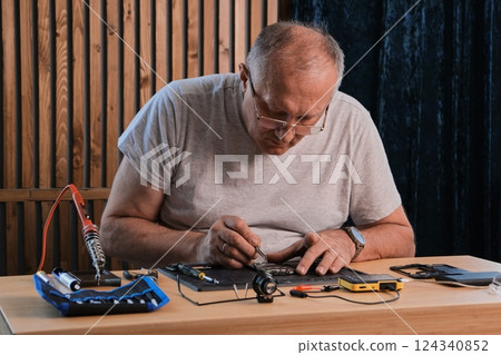 Men wearing denim shirt working with electronic components at his home office Men wearing denim shirt working with electronic components at his home office 124340852