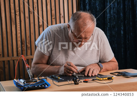Men wearing denim shirt working with electronic components at his home office Men wearing denim shirt working with electronic components at his home office 124340853
