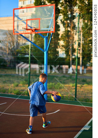 Boy in a blue tracksuit playing basketball 124340858