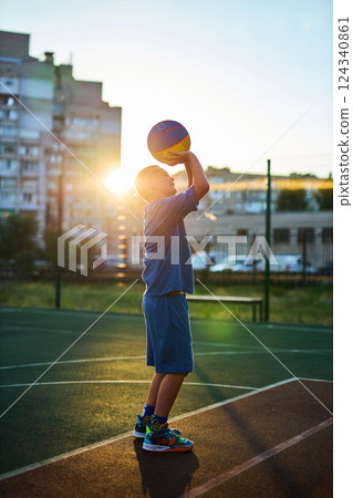Boy in a blue tracksuit playing basketball Boy in a blue tracksuit playing basketball 124340861