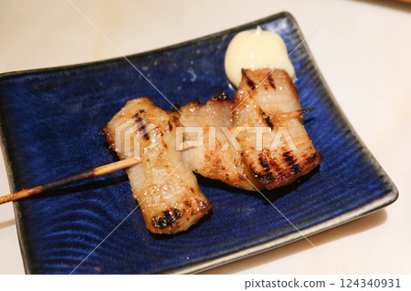 close up of Thai style grilled pork neck skewer with salad dressing on the side on a blue plate close up of Thai style grilled pork neck skewer with salad dressing on the side on a blue plate 124340931