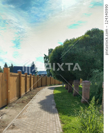paved path along a semi-circular wooden fence and trees, fenced private area paved path along a semi-circular wooden fence and trees, fenced private area 124340990