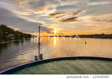 Golden sunset over the river, view from the motorboat on the calm water surface and houses on the shore, beautiful evening panorama Golden sunset over the river, view from the motorboat on the calm water surface and houses on the shore, beautiful evening panorama 124340997