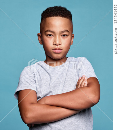 Problem, crossed arms and portrait of child with angry facial expression, attitude and upset over conflict on mockup studio. Anger, moody boy and unhappy African youth kid isolated on blue background Problem, crossed arms and portrait of child with angry facial expression, attitude and upset over conflict on mockup studio. Anger, moody boy and unhappy African youth kid isolated on blue background 124341432