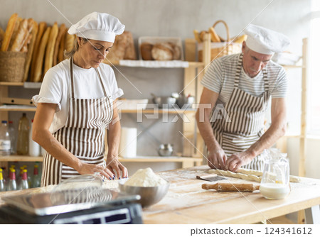 Two bakers prepare doughs for baking delicious bread - giving it the shape of baguette 124341612