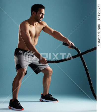 Fitness, studio and man with battle ropes for workout, exercise and body wellness. Muscle, shirtless bodybuilder and equipment for strength, power training and cardio endurance on blue background Fitness, studio and man with battle ropes for workout, exercise and body wellness. Muscle, shirtless bodybuilder and equipment for strength, power training and cardio endurance on blue background 124341742