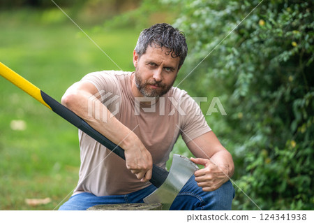 Lumberjack check sharp axe blade. Sweating man with axe. Lumberjack in woods with an ax. Lumberjack with heavy axe. Strong sweating man work in forest. Lumberjack man in forest with axe 124341938